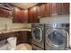 Well-equipped laundry room with dark wood cabinets, granite countertops, a sink, and modern washer/dryer at 226 W Crimson Sky Ct, Casa Grande, AZ 85122