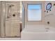 Bright bathroom featuring a shower with glass enclosure, a soaking tub and large window for natural light at 230 S 122Nd Ln, Avondale, AZ 85323