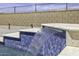 Detail of a modern swimming pool waterfall feature with blue tile and stone accents at 2354 E Lieber Pl, Phoenix, AZ 85024
