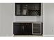 Elegant wet bar featuring dark cabinetry, wine storage, granite countertops, and a wine refrigerator at 2354 E Lieber Pl, Phoenix, AZ 85024