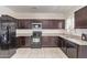 Functional kitchen featuring dark wood cabinets, granite countertops, and modern appliances for cooking at 29109 N Fire Agate Rd, San Tan Valley, AZ 85143