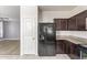 Convenient layout of a kitchen featuring black fridge, dark wood cabinets, and an adjacent living space at 29109 N Fire Agate Rd, San Tan Valley, AZ 85143