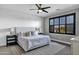 Comfortable bedroom with a ceiling fan, large window with black shutters, and elegant lamps at 3169 E Eleana Ln, Gilbert, AZ 85298