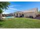 Backyard featuring lush green grass, rock waterfall feature, a covered patio, and partial perimeter fencing at 4030 E Meadow Creek Way, San Tan Valley, AZ 85140