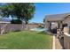 This backyard features a pool, lush green grass, rock waterfall feature, a covered patio, and block fencing at 4030 E Meadow Creek Way, San Tan Valley, AZ 85140