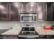 Close up on a stove top with granite countertops and dark wood cabinetry in a well-equipped kitchen at 44468 W Eddie Way, Maricopa, AZ 85138