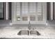 Close-up of a stainless steel kitchen sink featuring granite countertops and white shuttered windows at 44468 W Eddie Way, Maricopa, AZ 85138