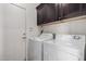 Laundry room with a side by side washer and dryer and dark cabinets above at 44468 W Eddie Way, Maricopa, AZ 85138