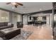 Spacious living room features a gray sectional sofa, ottoman, a view into dining area and tile flooring at 44468 W Eddie Way, Maricopa, AZ 85138