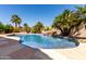 Inviting backyard pool with a rock waterfall feature surrounded by lush landscaping and tall palm trees at 44468 W Eddie Way, Maricopa, AZ 85138
