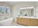 Bright bathroom featuring a double vanity, white countertops, and a modern standalone tub at 5430 E Shea Blvd, Scottsdale, AZ 85254