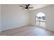 Clean bedroom with light wood floors, ceiling fan, white walls and a modern arch window at 5534 W Calavar Rd, Glendale, AZ 85306