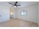 Bright bedroom with light wood floors, a ceiling fan, and a window overlooking the backyard bathroom at 5534 W Calavar Rd, Glendale, AZ 85306
