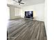 Bright living room featuring wood-look floors, a ceiling fan, and a large tv on a floating entertainment center at 5952 W Morning Dove Dr, Glendale, AZ 85308