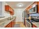 Well-lit kitchen with stainless steel appliances, light-colored wood flooring, granite counters, and wood cabinets at 623 W Guadalupe Rd # 213, Mesa, AZ 85210