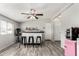 An entertainment area featuring a bar with three stools, a mounted ceiling fan, and gray wood flooring at 7011 W Carol Ann Way, Peoria, AZ 85382