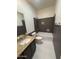 Bathroom with a granite vanity, gray tiled shower/tub, and white floors at 7111 S 21St Dr, Phoenix, AZ 85041