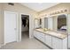 Well-lit bathroom featuring dual sinks, a large mirror, and access to a walk-in closet at 9012 E Sutton Dr, Scottsdale, AZ 85260