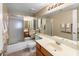Well-lit bathroom with a large mirror, neutral tile, and a shower-tub combination with sliding glass doors at 9012 E Sutton Dr, Scottsdale, AZ 85260
