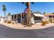 Charming manufactured home with desert landscaping, covered porch and an American flag on a palm tree at 9333 E University Dr # 83, Mesa, AZ 85207