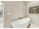 Modern bathroom showcasing a freestanding tub, neutral-toned tile, and a decorative piece of wall art at 11334 E Troon Vista Dr, Scottsdale, AZ 85255