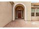 Covered front entrance with a decorative arched entry and a beautiful wood door at 12906 W Oyer Ln, Peoria, AZ 85383