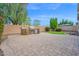 A stone outdoor kitchen offers backyard barbeque capabilities amid lush trees and synthetic grass at 134 E Bernie Ln, Gilbert, AZ 85295