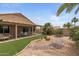 Beautiful backyard with covered patio, artificial turf, desert landscaping, and mature trees, perfect for relaxation and entertaining at 16205 W Mountain Pass Dr, Surprise, AZ 85374