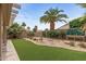 Lush backyard featuring well-manicured artificial turf, a rock garden, and mature landscaping including palm trees at 16205 W Mountain Pass Dr, Surprise, AZ 85374