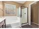 Bright bathroom featuring a tub with shower, a separate glass-enclosed shower, and a block glass window at 16987 W Hammond St, Goodyear, AZ 85338