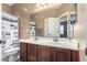 Bathroom featuring double sinks, wood cabinets, large mirror, and decorative shower curtain at 16987 W Hammond St, Goodyear, AZ 85338
