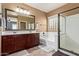 Well-lit bathroom with a double vanity, large mirror, soaking tub, and glass-enclosed shower at 16987 W Hammond St, Goodyear, AZ 85338