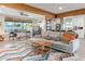 Open-concept living room featuring exposed wood beam, modern furniture, with view into bright, well-appointed kitchen at 1702 W Glenrosa Ave, Phoenix, AZ 85015
