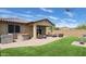 A relaxing covered patio with wicker furniture, an artificial lawn, and a hot tub for outdoor enjoyment at 17211 W Whispering Wind Rd, Surprise, AZ 85387