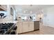 Bright, modern kitchen with stainless appliances, white cabinets and island, and tiled floors; open to living space at 17211 W Whispering Wind Rd, Surprise, AZ 85387