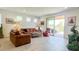 Bright living room featuring tile floors, neutral walls, brown leather couches, and sliding door to backyard patio at 17211 W Whispering Wind Rd, Surprise, AZ 85387