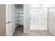 Bright bathroom featuring glass-enclosed shower with tiled floor and shelving unit at 17977 W Camino De Oro Riv, Surprise, AZ 85387