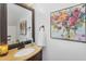 A bathroom with vanity and framed mirror is accented by a floral painting at 18811 N 34Th Ave # 6, Phoenix, AZ 85027