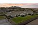 Expansive aerial view of a home with a lush green lawn, a tennis court and mountain backdrop at 18826 E Augusta Ave, Queen Creek, AZ 85142