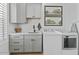 Bright laundry room with white appliances, gray cabinets, and a functional sink area at 18826 E Augusta Ave, Queen Creek, AZ 85142