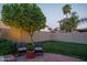 Relaxing backyard with a brick patio, a fire pit, a fruit tree, and a privacy fence at 19115 N 71St Dr, Glendale, AZ 85308
