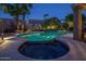 Backyard pool with jacuzzi, covered outdoor kitchen, lush landscaping, and ambient lighting at 19115 N 71St Dr, Glendale, AZ 85308