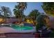 Sparkling pool features lush landscaping, including palm trees and a mosaic waterfall, creating a tranquil backyard escape at 19115 N 71St Dr, Glendale, AZ 85308