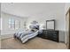 Bedroom with window shutters, two bedside tables, dresser, and a decorative mirror on the wall at 19225 N Tallowood Way, Surprise, AZ 85387