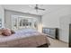 Bright bedroom featuring a bay window with shutters, ceiling fan, and a luxurious pink comforter at 19225 N Tallowood Way, Surprise, AZ 85387