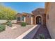 View of arched front entrance with stone surround and mature desert landscaping at 19225 N Tallowood Way, Surprise, AZ 85387
