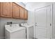 Well-lit laundry room with washer, dryer, overhead cabinets, and convenient access door at 19225 N Tallowood Way, Surprise, AZ 85387