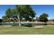 Peaceful view of a pond with a fountain, grassy area and bench seating under a shady tree at 20298 N 108Th Ln, Sun City, AZ 85373