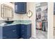 Stylish bathroom with blue vanity, a vessel sink, decorative mirror and walk-in closet at 20423 W Springfield St, Buckeye, AZ 85396