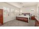 Spacious bedroom featuring a wood-framed bed, light gray carpet and natural light from shuttered windows at 20423 W Springfield St, Buckeye, AZ 85396